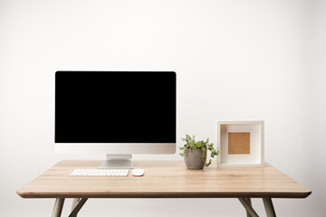 workplace with green plant, photo frame and desktop computer with copy space isolated on white