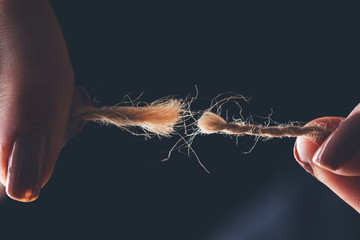 Breaking rope in hands on the dark background