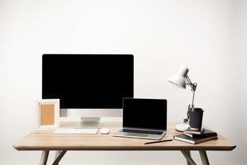 workplace with photo frame, coffee to go, notebooks, desktop computer and laptop with copy space isolated on white