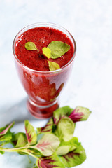 Red drink with green  spinach leaves and paper straw in tall glass on bright background. Superfoods, healthy lifestyle concept. Vegetarian food. Detox. Diet. Text space