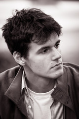 Obraz premium Portrait of a young man outside, wearing a denim jacket in black and white