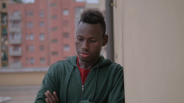 Serious proud young american african man leaning against wall,looks at camera