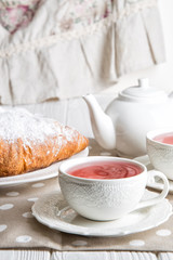 Close up. French breakfast. Freshly baked golden croissants and berry tea in vintage porcelain cups. Copy space.