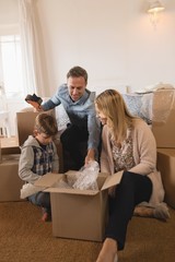 Family unpacking cardboard boxes in their new home