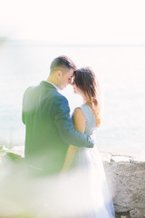 Beautiful young couple embracing and walking in the garden of the Scaliger Castle on the background of Garda Lake. Sirmione, Italy