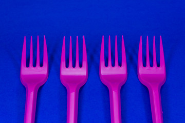 Pink plastic forks on blue background