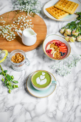 spring breakfast on the table with green tea latte with oatmeal, waffles and flowers