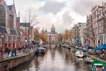 The Oudezijds Voorburgwal canal in the Red-light district in the center of Amsterdam with Basilica of St. Nicholas.