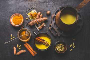 Healthy ingredients of turmeric milk drink with fresh turmeric roots , spices and honey. Hot winter...