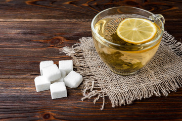 Sugar and green tea with lemon on wooden background.