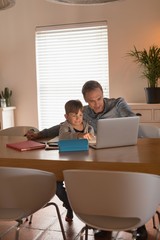 Father helping his son with his homework while using laptop