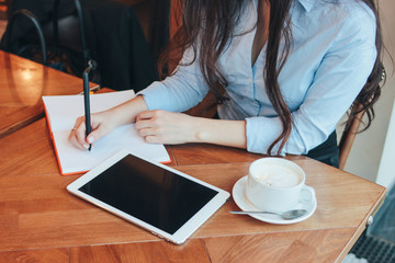 Beautiful charming brunette girl with tablet at table in cafe, student, freelancer