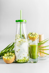Healthy vegan matcha kiwi latte drink in bottle with drinking straw and matcha espresso standing on table at light background.  Clean eating, detox beverage, dairy food concept. Tasty summer drinks