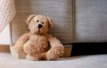 Teddy bear is sitting down on carpet in retro filter, Lonely teddy bear sitting alone in living room in sunny day, Lonely concept, International missing children's day.