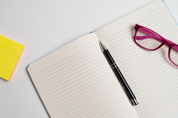 Notebook with black pen, Colorful notepads on the desk, Glasses on the desk with pen and cup of coffee, Computer keyboard with colorful note stick