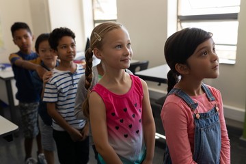 School kids standing in row in classroom of elementary school