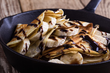Crepes with bananas and chocolate topping for breakfast