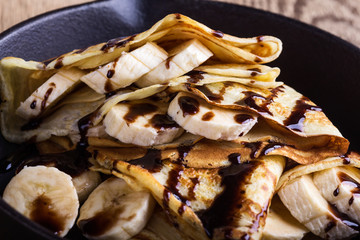Crepes with bananas and chocolate topping for breakfast