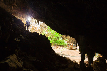 Young man exploring mystic cave with torch.
