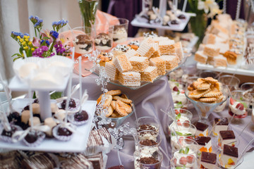 Obraz na płótnie Canvas Buffet table with sweets and desserts on the table. Wedding candy bar with delicious cupcakes, cake pops, biscuits, flowers.