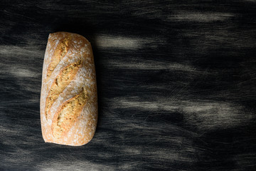 Loaf of bread on dark wooden background