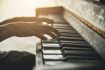 Old person's hands playing the piano. Close up view of skin texture and piano keys.