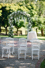 Wedding ceremony with beautiful floral wedding arch of white roses in the garden. Arch. Floristics.