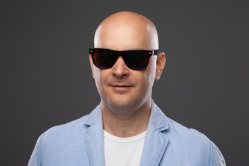 Fototapeta premium bald man in black glasses on a gray background