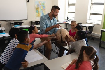 Male teacher teaching his kids about geography by using globe in