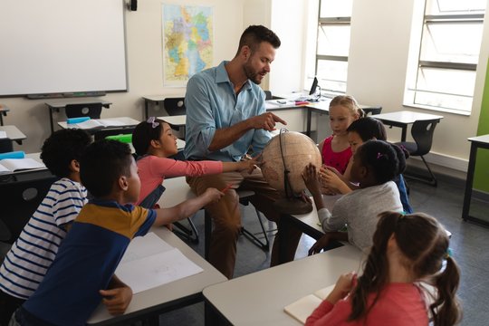 Male Teacher Teaching His Kids About Geography By Using Globe In