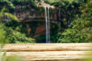 Wooden table on the background of a waterfall on a summer day   