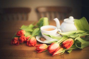 Fototapeta na wymiar tulips and Breakfast on the kitchen table . spring flowers and a Cup of tea in the morning. international women's day or mother's day