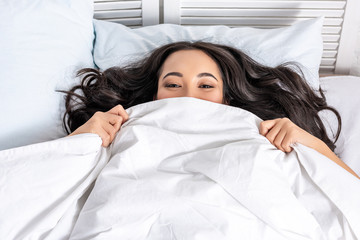 Young asian beautiful woman hiding under blanket