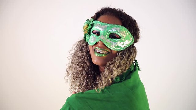 Beautiful Brazilian black female model posing in carnival mask with bright makeup and gren lipstick. Covering with Brazilian flag.