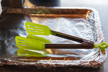 Plastic Food Tongs on aluminum foil wrapped tray for picking hot toasted bakery at breakfast in...
