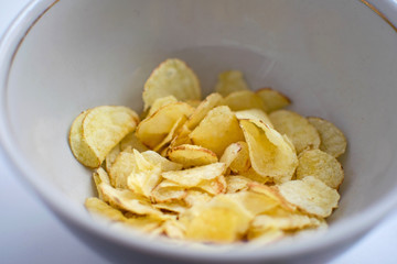 Potato chips in a plate on a white background. A white plate with tasty potato chips.