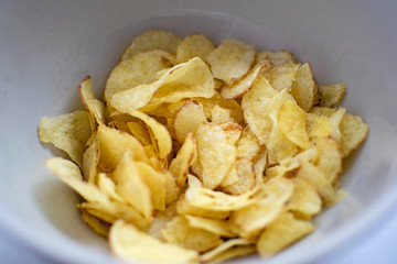 Potato chips in a plate on a white background. A white plate with tasty potato chips.