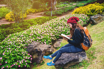 woman travel nature in the flower garden. relax sitting on rocks and reading books In the midst of nature at national park doi Inthanon.