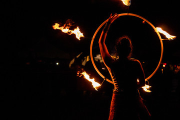 fire-eater, fire dancer with flaming hoop in night show at medieval festival with black background