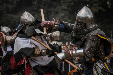 Medieval knights fighting with armor, beating with swords, axes and shields in festival