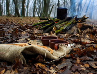 cup of tea with spoon and ring-shaped roll on bonfire