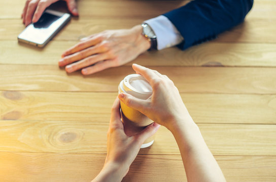 Barista serves coffee to a man. Hand Paper cup Plastic cap Wooden table Break Blazer. Coffee Break Concept