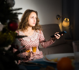 Young woman is sitting with champagne in New Year night at home