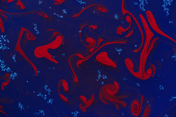 abstract red drops of paint on dark deep blue background with glitter