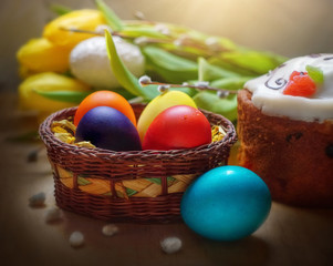 Fototapeta na wymiar Painted eggs in a basket and Easter cake on a background of flowers