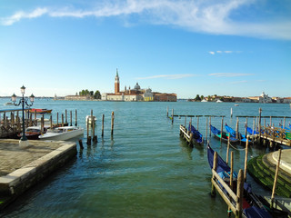 Amazing view to Basilica di San Giorgio Maggiore with gondolas in Venetian Lagoon under blue sky, Venice, Italy