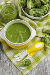 Fresh broccoli in the bowl, and portion of puree made from crushed broccoli, blurred background