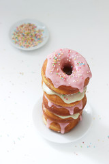 Homemade donuts decorated with colored icing and colored sugar on a light background.