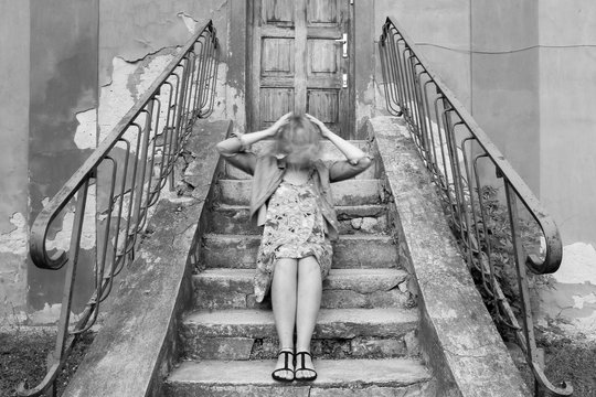 A picture of a girl sitting on stairs, holding her moving head. Looking confused and lost. 