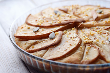 gorgeous pie with pears in a glass container on wooden background